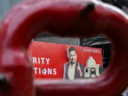 Ein Mann ist auf einem roten Werbeplakat im Stadtgebiet abgebildet, das moderne Werbemaßnahmen illustriert.