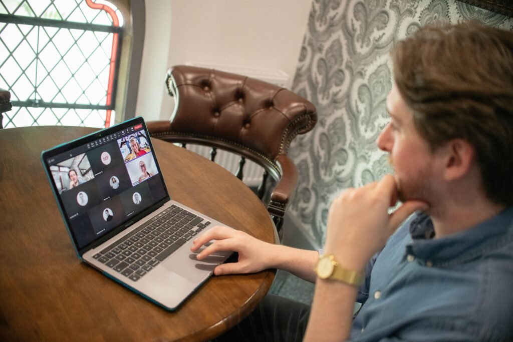 Ein Mann sitzt an einem Schreibtisch und nimmt mit seinem Laptop an einer Video-Konferenz teil