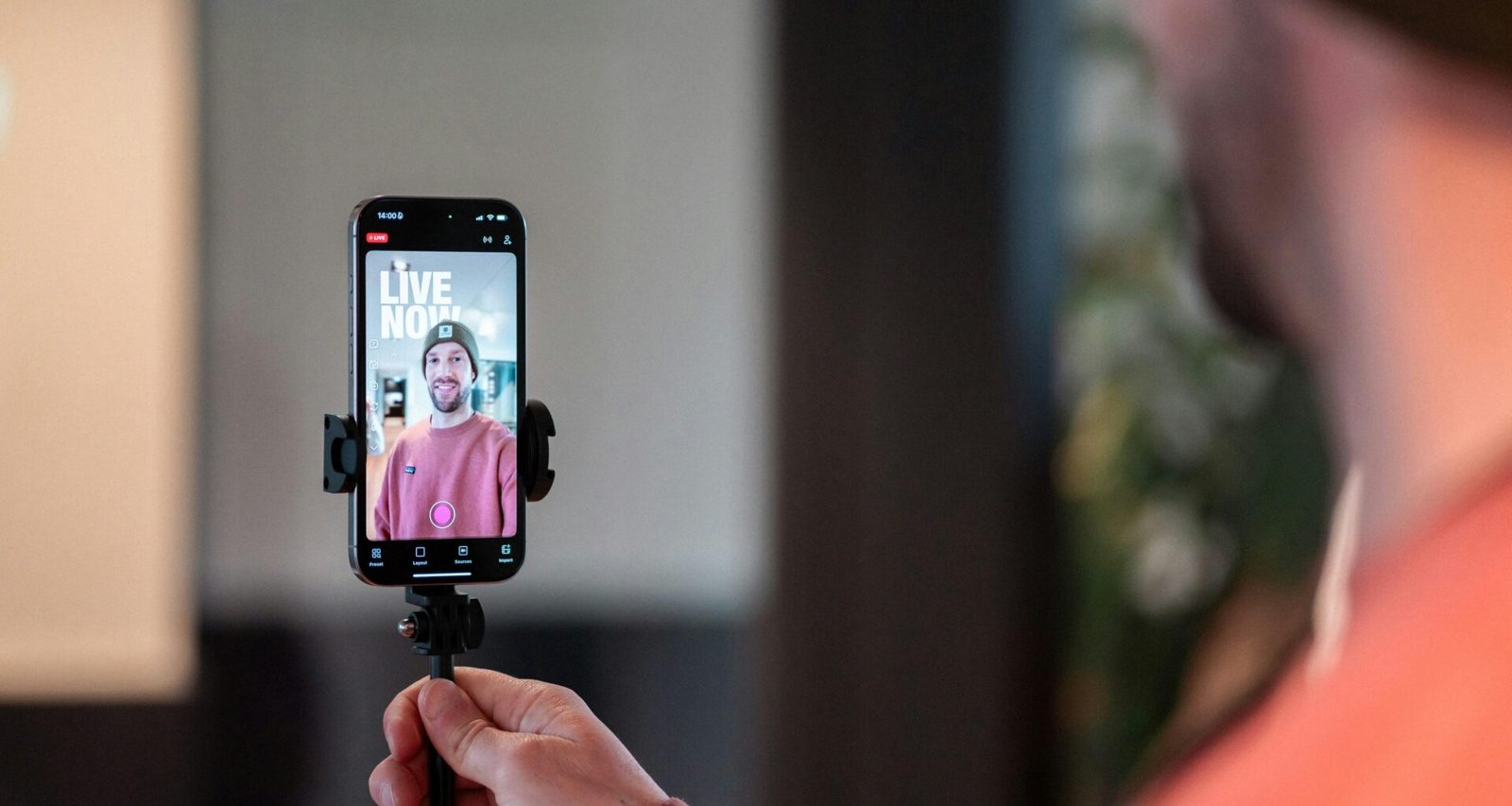 Mann filmt sich selbst mit einem Smartphone bei einem Livestream, Fokus auf mobile Videoaufnahme