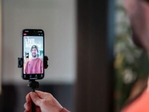 Mann filmt sich selbst mit einem Smartphone bei einem Livestream, Fokus auf mobile Videoaufnahme