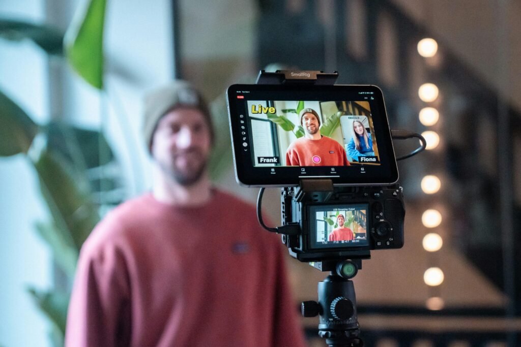 Mann filmt ein Video mit professioneller Kamera und Monitor bei der Arbeit in einem modernen Studio.