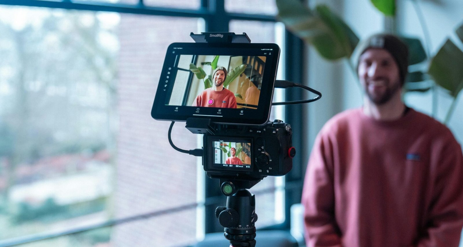 Mann richtet Kamera mit angeschlossenem Monitor auf sich, um ein Selbstportrait-Video aufzunehmen, moderne Technik im Einsatz