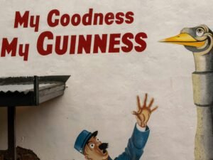 Ein Mann streckt den Arm aus, um eine Gänsestatue mit eingefügtem Text zu erreichen, Symbolik im Fokus.