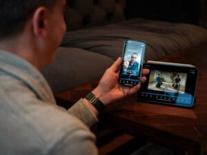 Ein Mann hält ein Smartphone in der Hand und schaut sich ein Video auf dem Bildschirm an, Alltagsszene digitaler Mediennutzung.