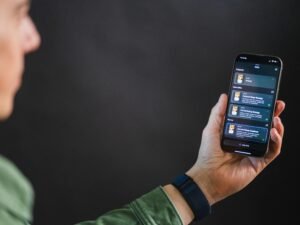 Ein Mann hält ein Smartphone in der Hand und betrachtet das Display mit einer modernen App-Oberfläche.