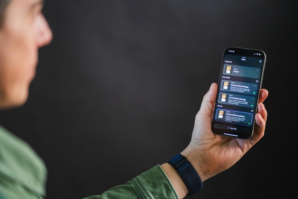 Ein Mann hält ein Smartphone, auf dessen Bildschirm eine App-Oberfläche zu sehen ist, Fokus auf die moderne Benutzeroberfläche.