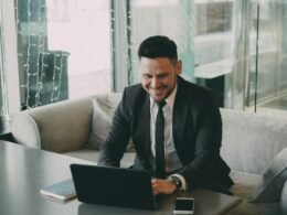 Geschäftsmann im Anzug sitzt an einem Schreibtisch und arbeitet konzentriert an einem Laptop in modernem Büro.