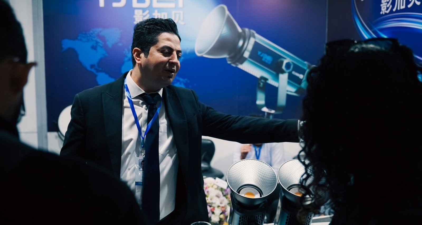 Ein Mann im Anzug stellt technische Geräte auf einer Fachmesse vor, moderne Ausstattung und Innovationen im Fokus.