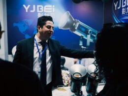 Ein Mann im Anzug stellt technische Geräte auf einer Fachmesse vor, moderne Ausstattung und Innovationen im Fokus.