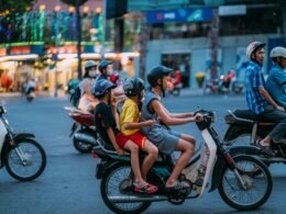 Mann und Frau in gelben Shirts fahren gemeinsam auf einem Motorrad durch die Stadt