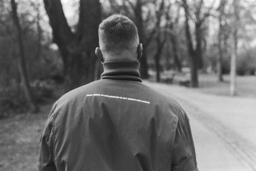 Mann im schwarzen Hemd steht auf einer leeren Straße in einer Schwarzweißfotografie, moderner und zeitloser Bildstil.