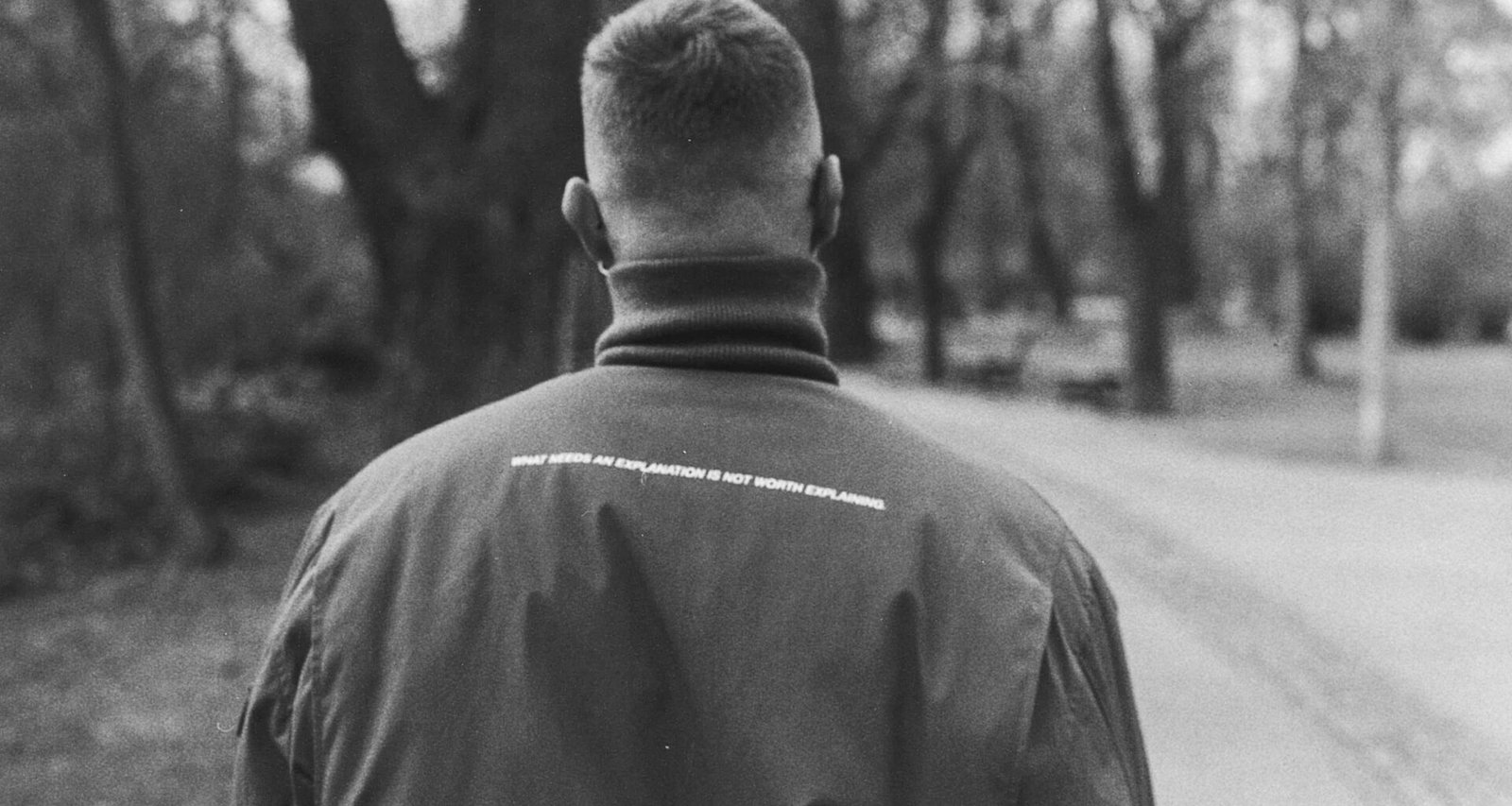 Mann im schwarzen Hemd steht auf einer leeren Straße in einer Schwarzweißfotografie, moderner und zeitloser Bildstil.