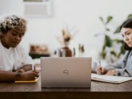 Mann im weißen Hemd arbeitet an einem Laptop an einem Schreibtisch in einem modernen Arbeitsumfeld