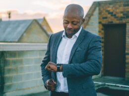 Ein Mann im grauen Anzug hält ein schwarzes Smartphone in der Hand und nutzt mobile Technologien im Büroalltag.