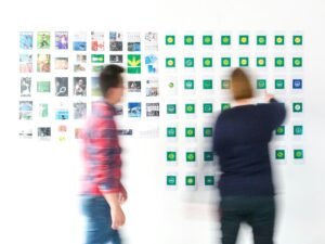 Ein Mann in schwarzem Langarmhemd steht neben einer Frau im rot-weiß karierten Hemd – Symbolbild für berufliche Kooperation