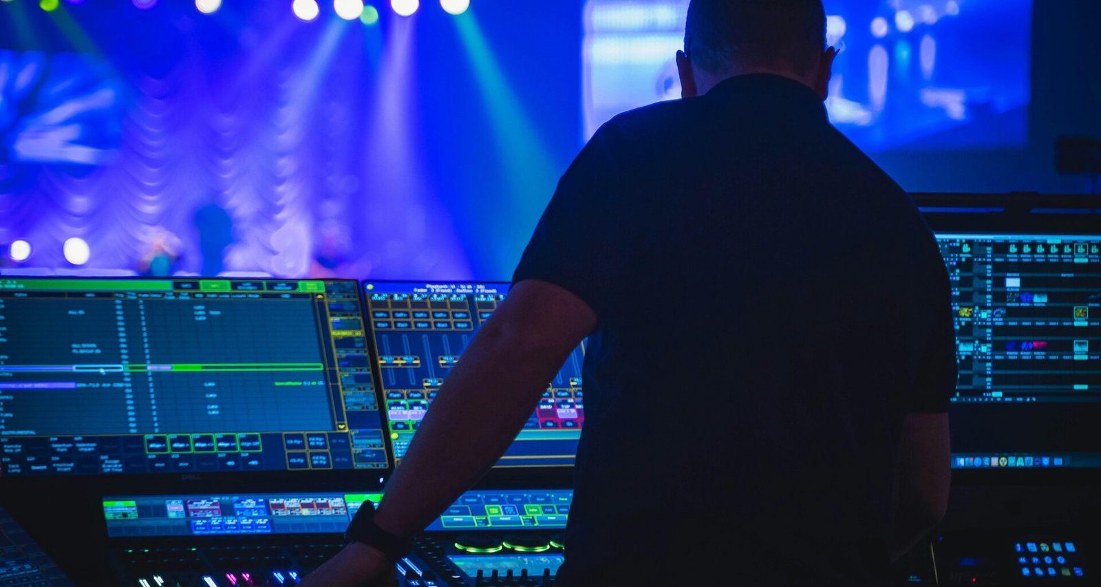 Ein Mann mit schwarzem T-Shirt bedient ein Audio-Mischpult in einem professionellen Tonstudio.