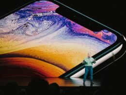 Ein Mann in weißem Hemd und blauen Jeans steht auf einer auffälligen blau-gelben Wasseroberfläche