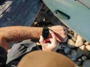 Mann steht im Freien und schaut auf seine Armbanduhr, um die aktuelle Zeit zu prüfen