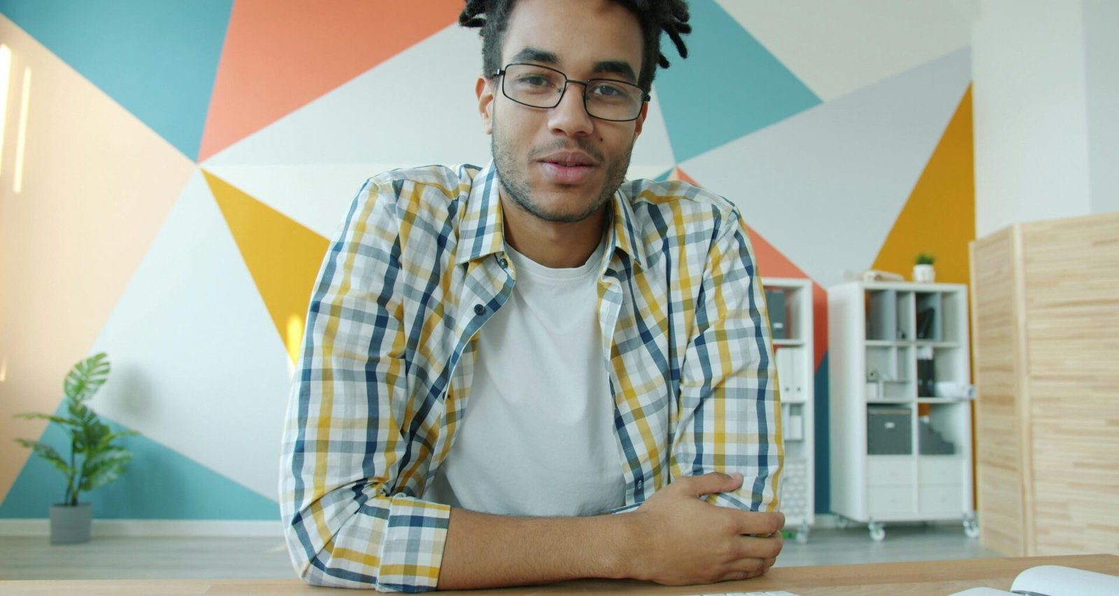 Mann mit Dreadlocks sitzt zu Hause und spricht in einem Videoanruf am Computer, Fokus auf Online-Kommunikation.