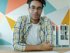 Ein Mann mit Dreadlocks sitzt entspannt vor seinem Laptop und nimmt an einem Videoanruf teil