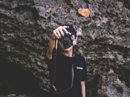 Ein Mann hält eine professionelle DSLR-Kamera in den Händen und steht bereit zum Fotografieren.