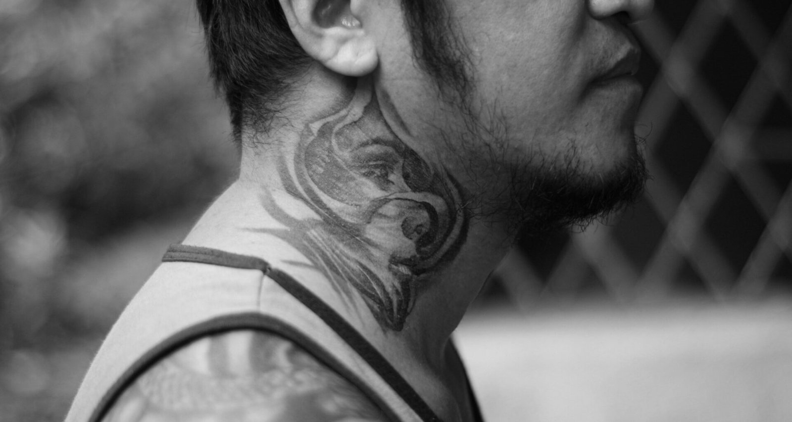 Mann mit sichtbarem Tattoo auf der rechten Wange, neutraler Hintergrund, aufgenommen von Mike Jumapao