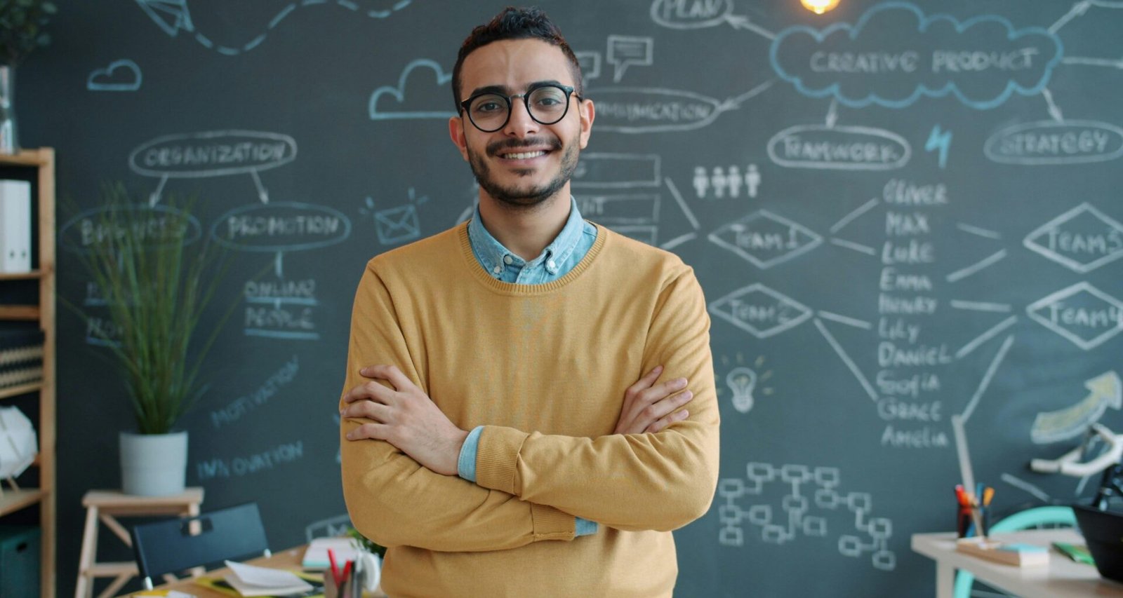 Mann mit verschränkten Armen steht nachdenklich vor einer Kreidetafel, ideal für Artikel zu Strategie oder Business-Themen.