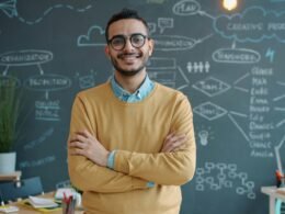 Mann mit verschränkten Armen steht nachdenklich vor einer Kreidetafel, ideal für Artikel zu Strategie oder Business-Themen.