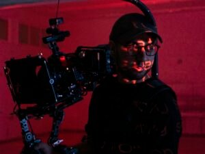 Ein Mann hält eine professionelle Videokamera in den Händen und richtet sie für Aufnahmen aus