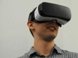 Ein Mann sitzt mit aufgesetztem VR-Headset und erlebt virtuelle Realität; konzentrierter Blick auf die Technologie.