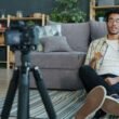 Ein Mann sitzt zu Hause und nimmt sich selbst mit einer Digitalkamera auf, um hochwertige Videos zu produzieren.