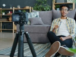 Ein Mann sitzt zu Hause und nimmt sich selbst mit einer Digitalkamera auf, um hochwertige Videos zu produzieren.