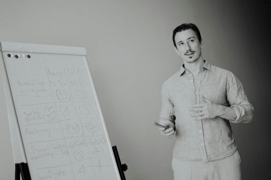 Ein Mann erklärt an einem Whiteboard im Meetingraum Ideen für das Team während einer Besprechung.