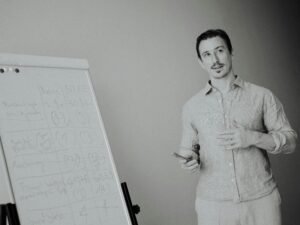 Ein Mann erklärt an einem Whiteboard im Meetingraum Ideen für das Team während einer Besprechung.