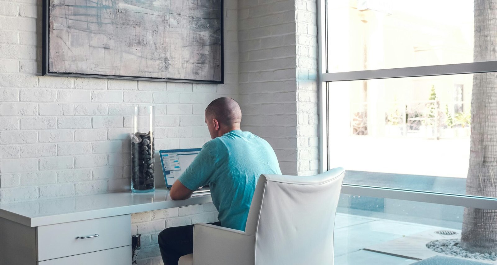 Ein Mann sitzt auf einem gemütlichen Sessel und benutzt einen Laptop-Computer, Umgebung im modernen Wohnstil gehalten.