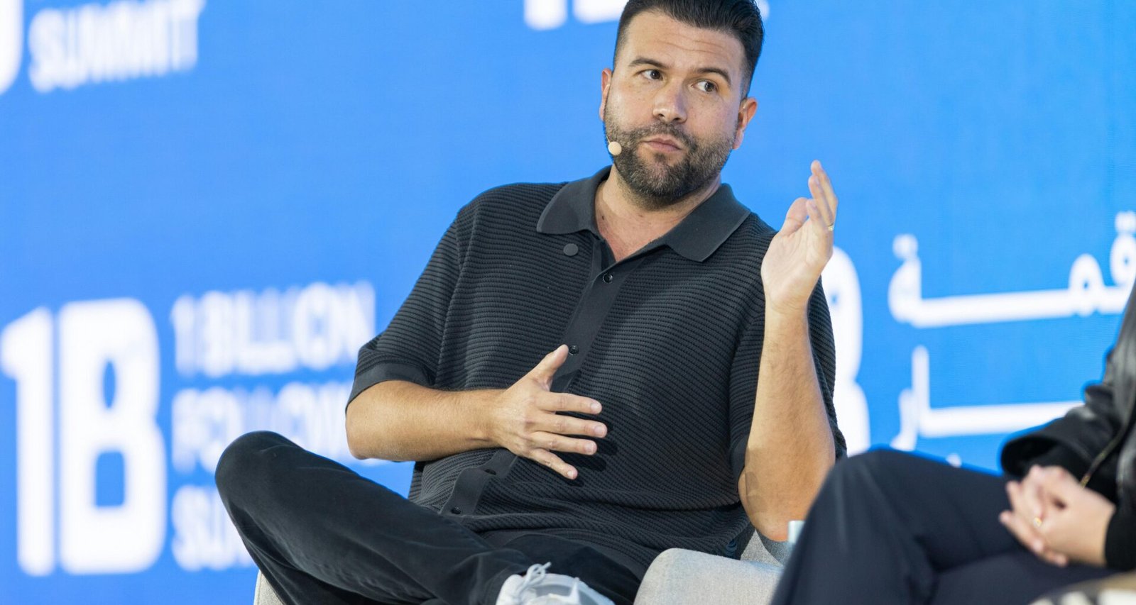 Mann auf einer Podiumsdiskussion vor blauem Hintergrund spricht über aktuelle Themen aus Technologie und Marketing