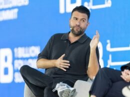 Mann auf einer Podiumsdiskussion vor blauem Hintergrund spricht über aktuelle Themen aus Technologie und Marketing