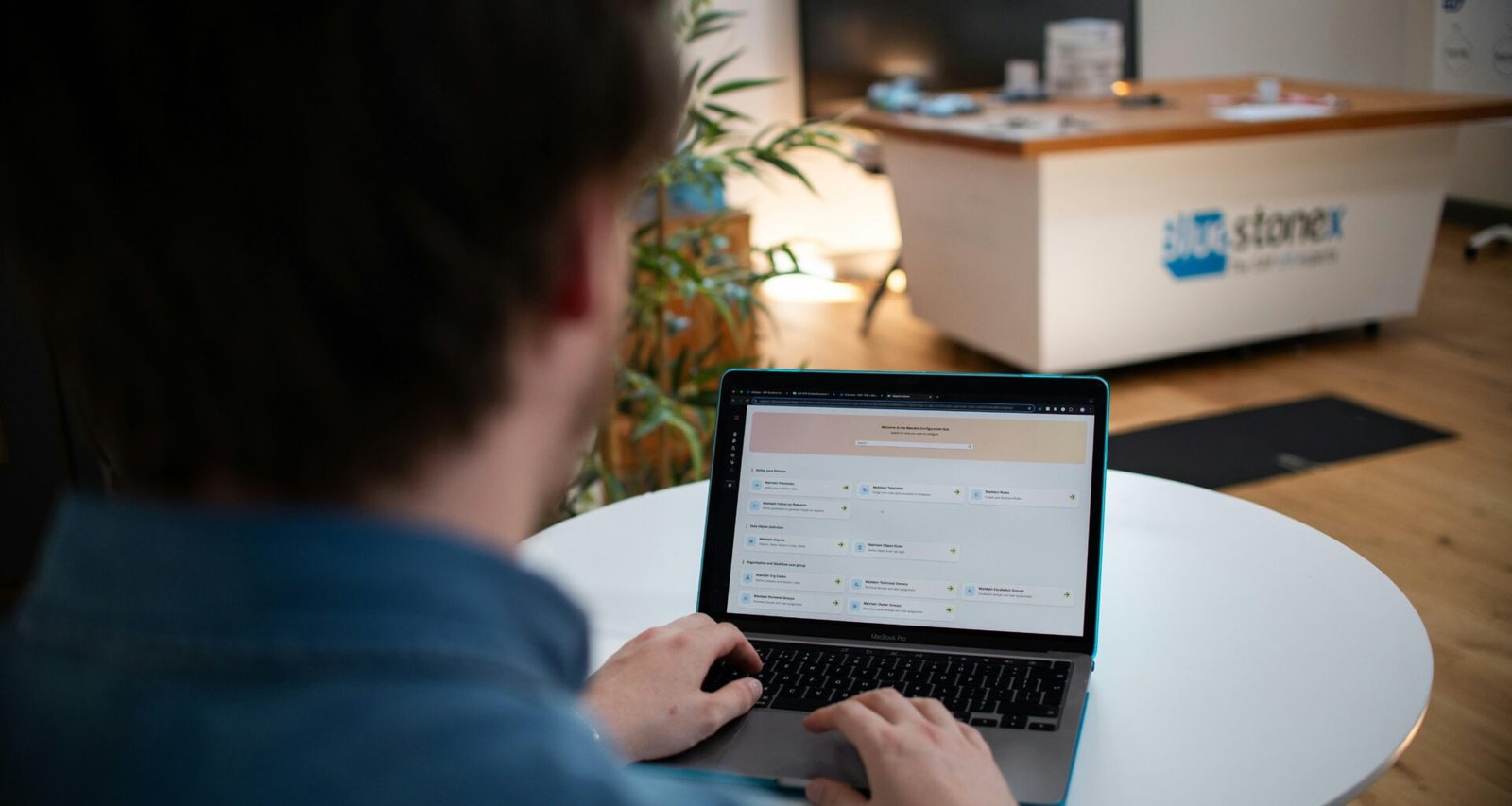 Mann arbeitet an einem Laptop, sitzt an einem weißen Tisch in moderner Umgebung, Fokus auf Hände und Tastatur