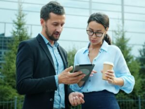 Ein Mann und eine Frau stehen vor einem Gebäude im Freien und schauen zusammen auf ein Tablet