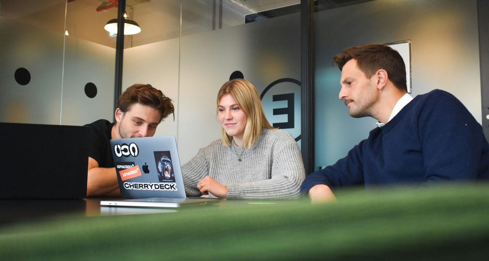 Ein Mann und eine Frau sitzen sich an einem Tisch gegenüber und arbeiten gemeinsam an Unterlagen und einem Laptop.