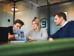 Ein Mann und eine Frau sitzen sich an einem Tisch gegenüber und arbeiten gemeinsam an Unterlagen und einem Laptop.