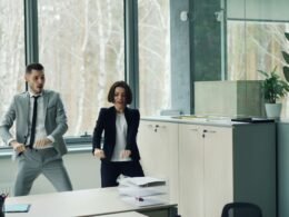 Ein Mann und eine Frau tanzen gemeinsam in einem modernen Büro und zeigen eine lockere Arbeitsatmosphäre.