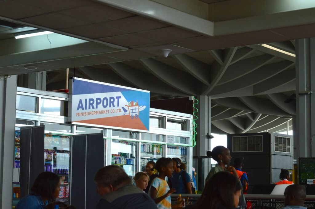 Menschen versammeln sich am Flughafen-Terminal nahe einem gut sichtbaren Schild, während sie auf ihren Flug warten.