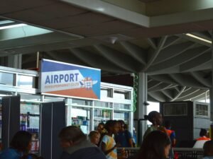 Menschen versammeln sich am Flughafen-Terminal nahe einem gut sichtbaren Schild, während sie auf ihren Flug warten.