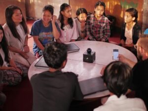 Mehrere Personen sitzen auf dem Boden vor einem niedrigen Tisch und arbeiten zusammen an einem Projekt in einem modernen Raum.