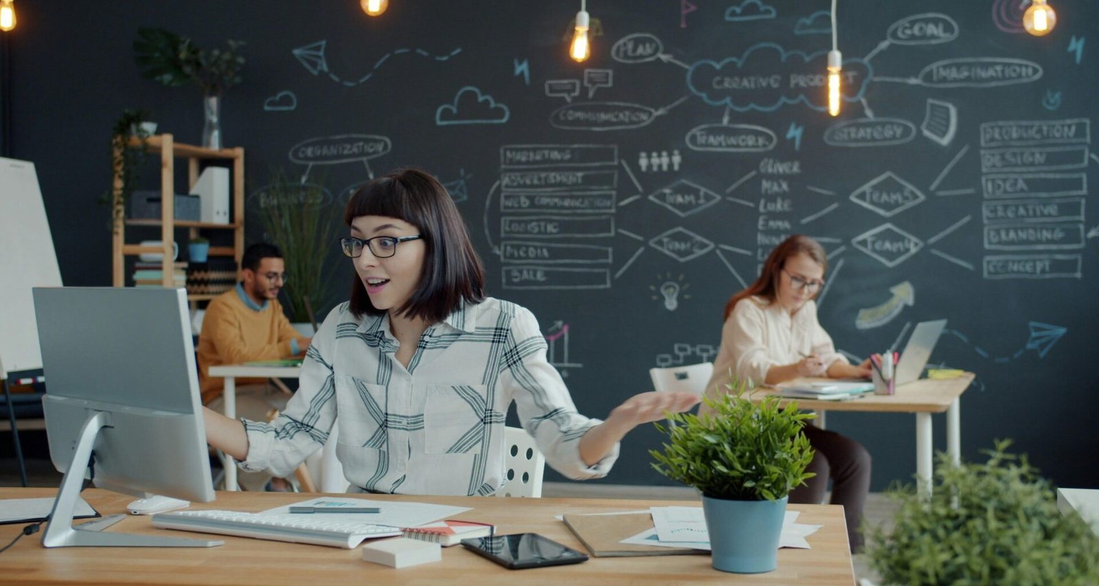 Menschen arbeiten zusammen in einem modernen Büro mit großen Tischen und Chalkboard-Zeichnungen an den Wänden