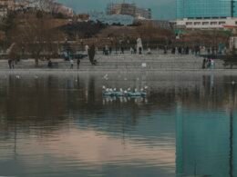 Mehrere Menschen in kleinen Booten auf einem ruhigen See, umgeben von Wasser, aufgenommen aus der Ferne.