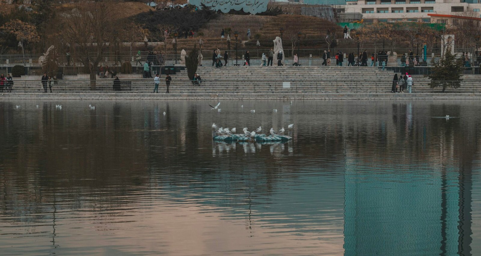 Mehrere Menschen in Booten auf einem ruhigen See, eingebettet in die natürliche Umgebung mit Wasser und Uferlandschaft.