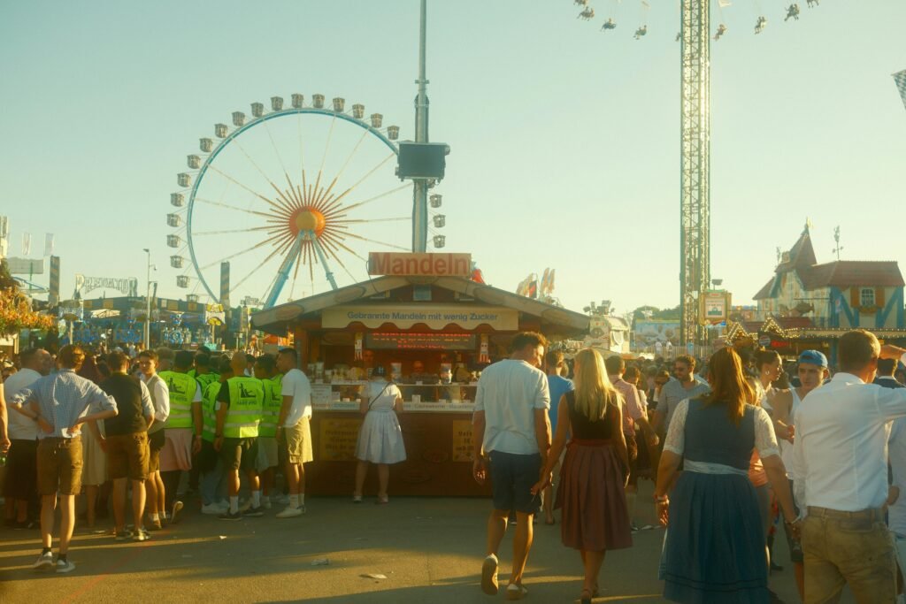 Große Menschenmenge bei sonnigem Wetter vor einem Riesenrad in einem Freizeitpark