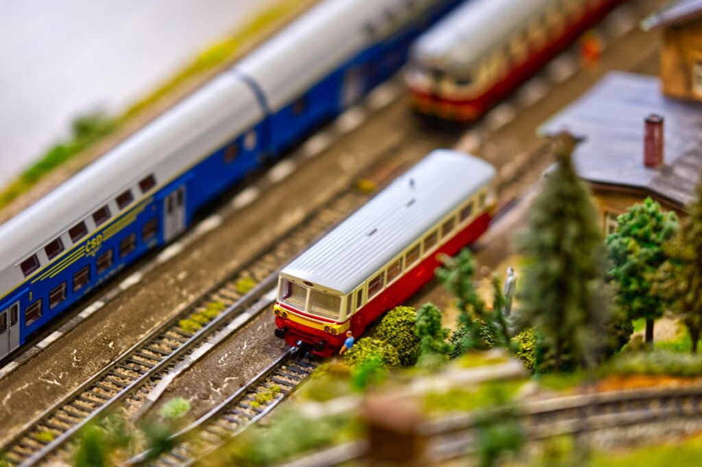 Miniaturzug mit mehreren Wagen fährt auf detailreichen Modelleisenbahn-Gleisen, aus der Vogelperspektive aufgenommen.